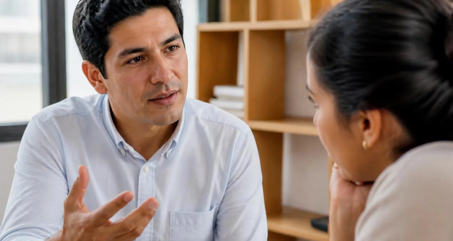 Dos personas conversando de cerca en una sala clara
